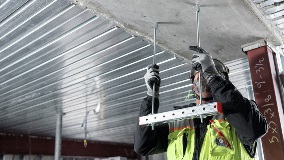 Worker installing overhead hanger assembly